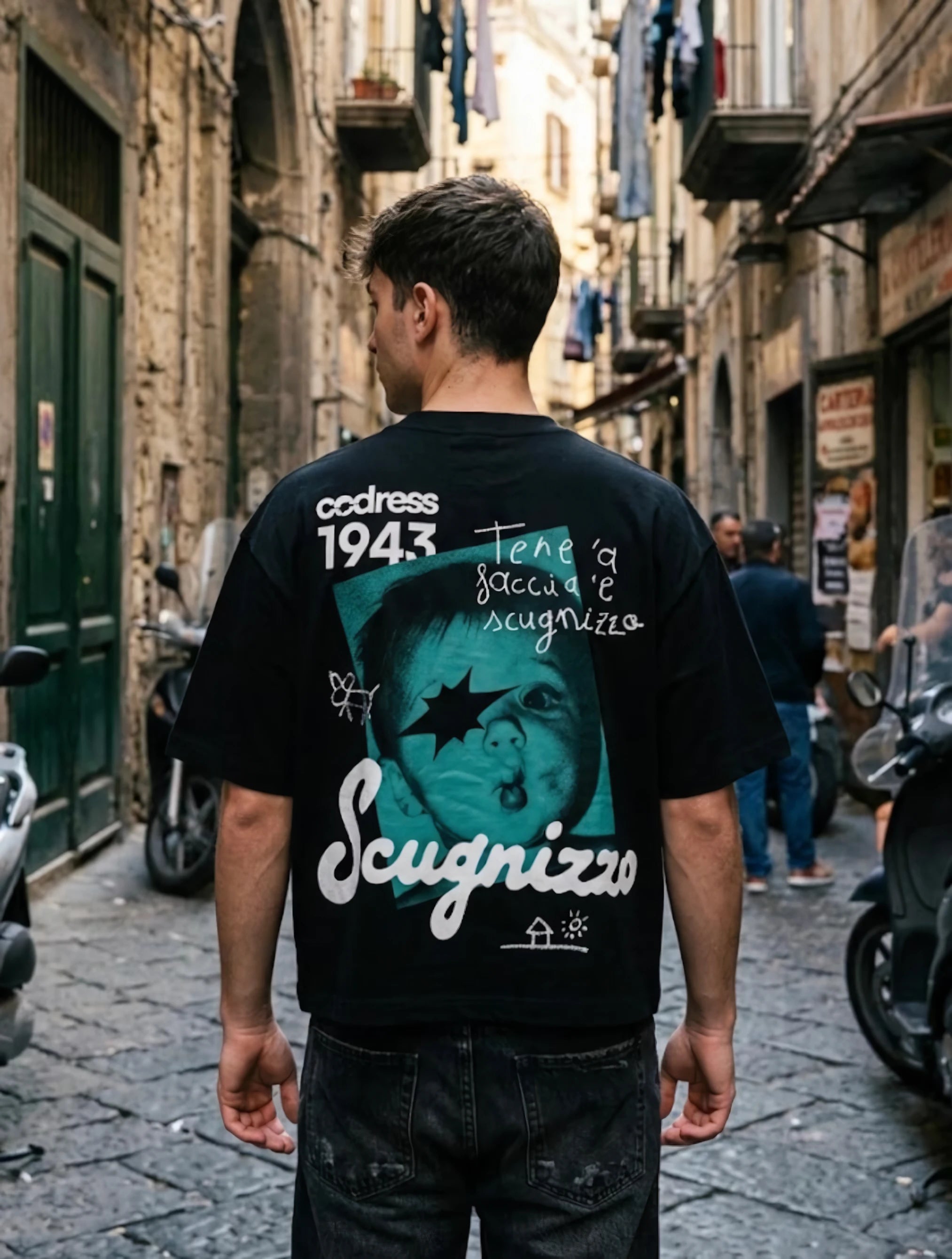 Chico de espaldas con la camiseta negra Scugnizzo 1943 en una calle de Nápoles.